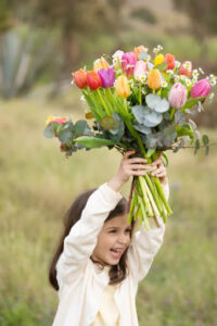 bambina che tiene in mano un bouquet di tulipani colorati