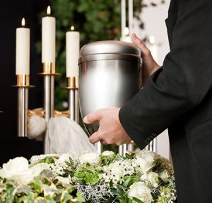 persona che tiene un'urna cremazione sfondo con fiori e candele