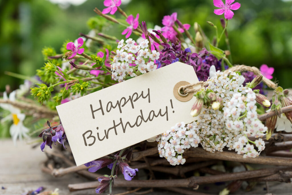 Bouquet di fiori con biglietto di auguri con scritto "Happy Birthday!"