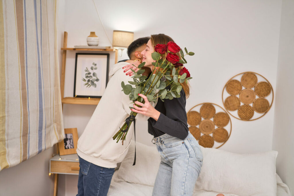 una ragazza e un ragazzo si abbracciano mentre lei tiene in mano un bouquet di rose rosse