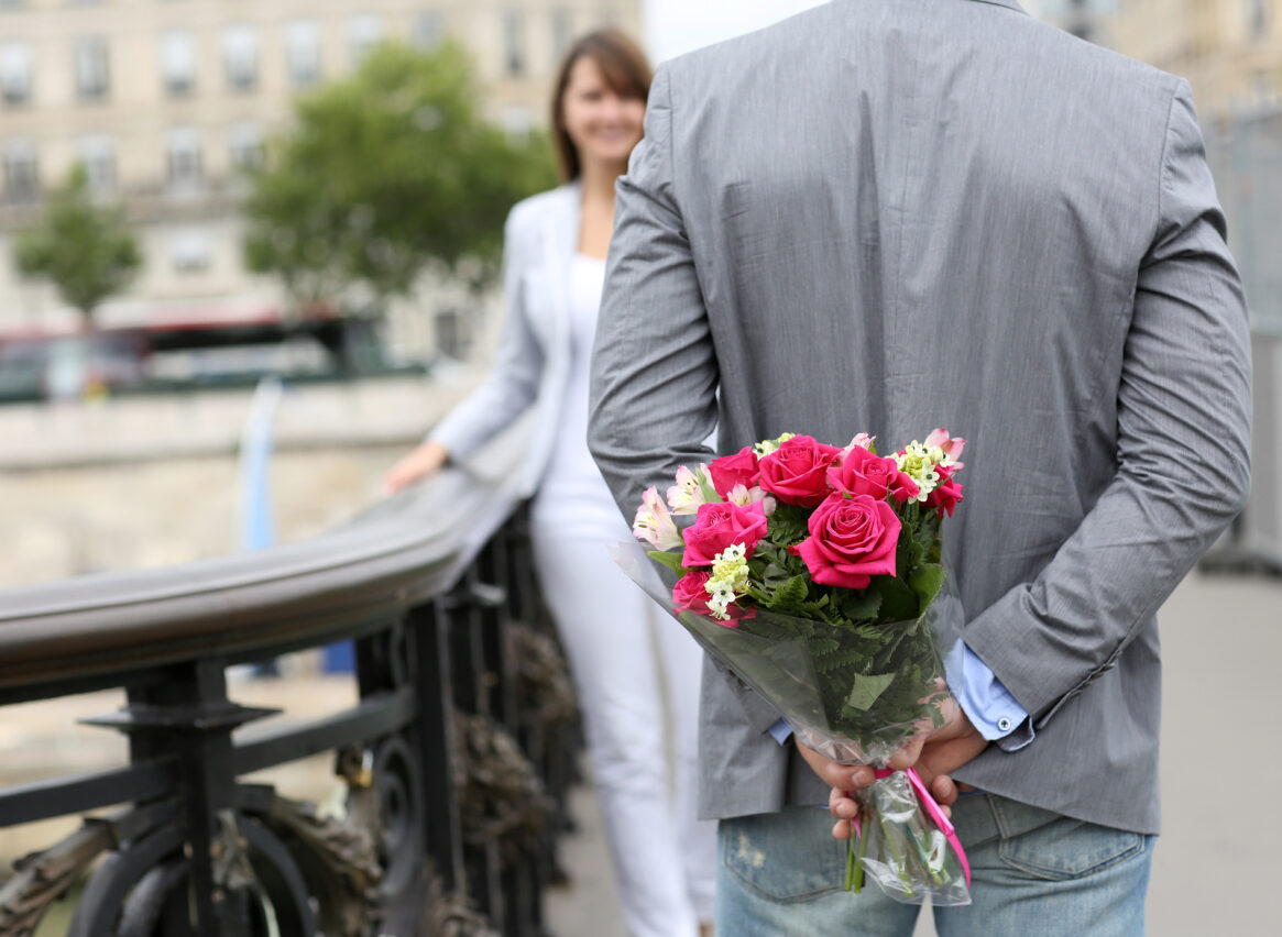 bouquet di fiori nascosto dietro la schiena di un uomo per corteggiare e conquistare