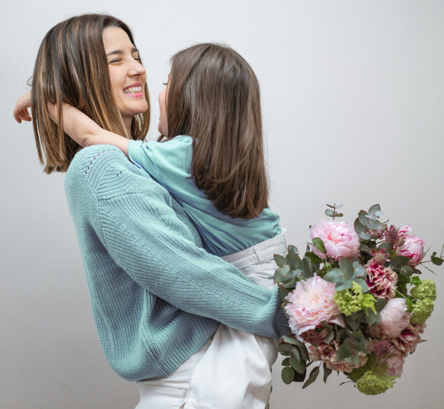 bambina in braccio alla mamma che tiene un bouquet mentre sorridono