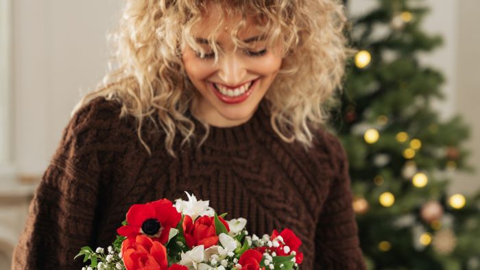 Ragazza che porta in mano un dono di Natale floreale.