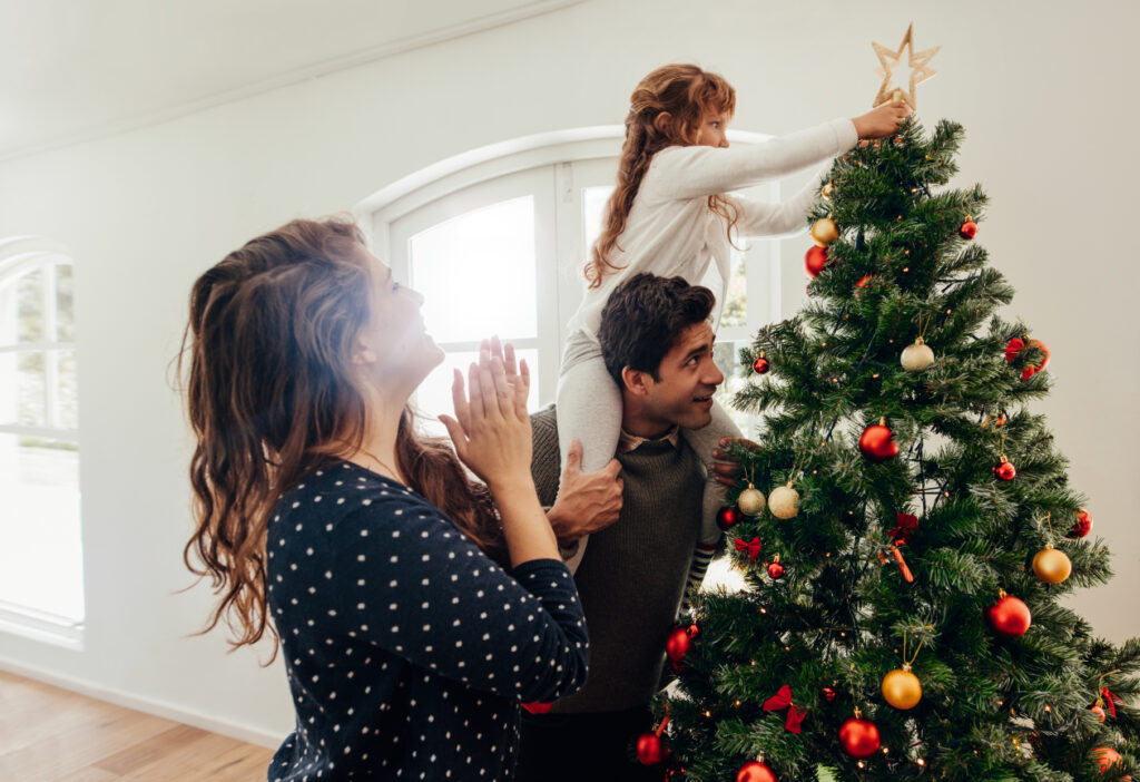 Famiglia che decora insieme l'albero di Natale l'8 dicembre.