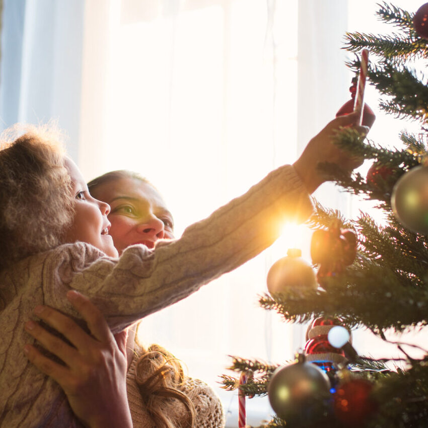 bambina felice che decora l'albero di Natale con la famiglia