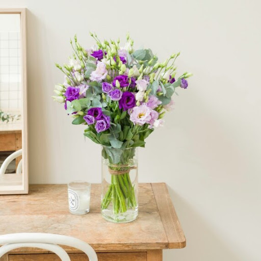 bouquet di lisianthus bianchi, verdi e viola in vaso trasparente